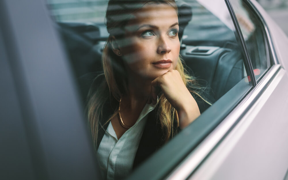 Frau schaut aus dem Fenster eines Fahrzeugs