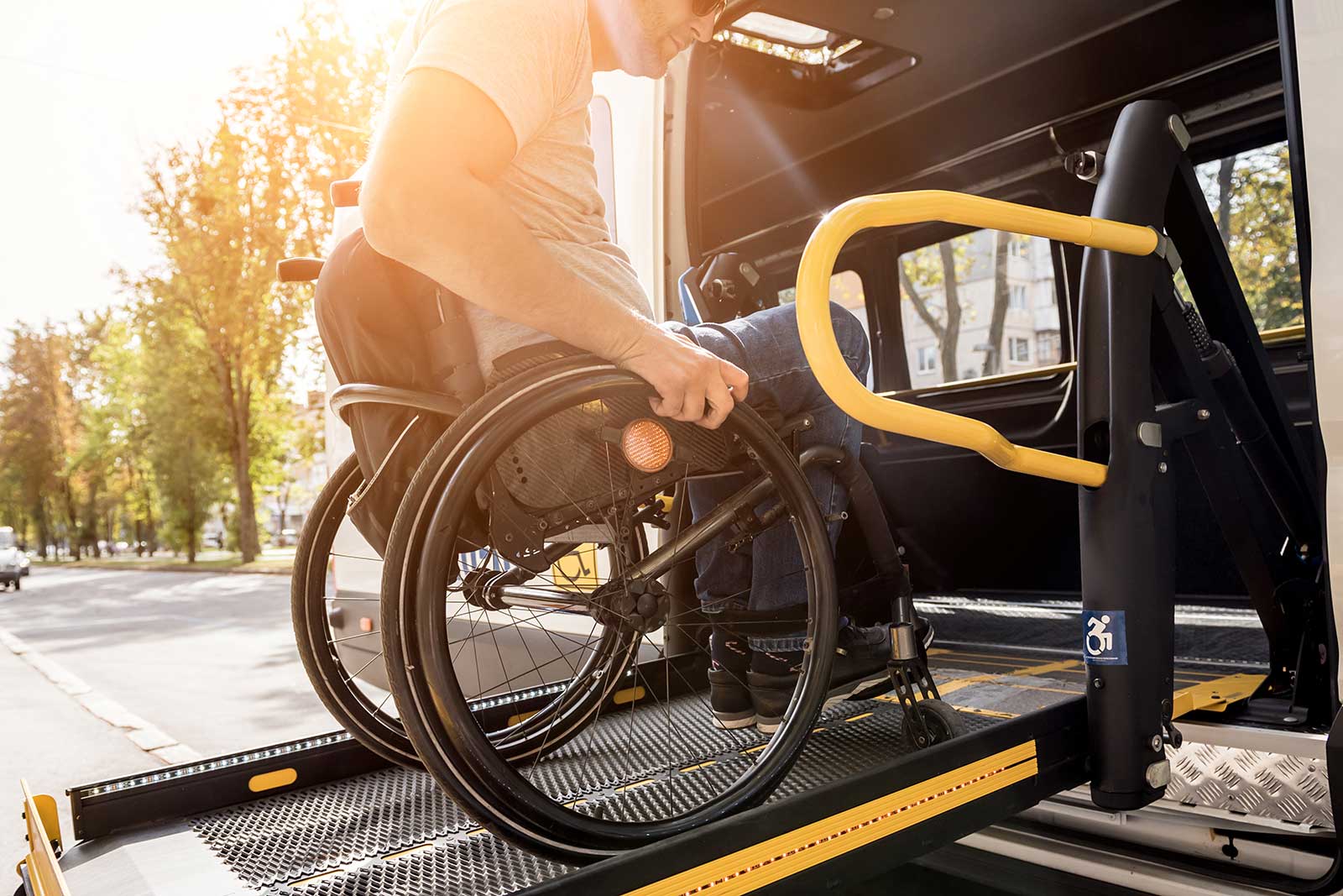 Ein Mann im Rollstuhl auf einem Aufzug eines Fahrzeugs für Menschen mit Behinderungen